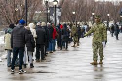 A member of the National Guard gives people direction standing in line at a COVID-19 vaccination site at Yankee Stadium.