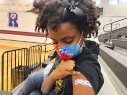 Solome Walker, 9, looks down at her bandage after getting her first Pfizer COVID-19 shot at a vaccination clinic for young students at Ramsey Middle School. 