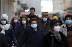 People wearing face masks to curb the spread of COVID-19 walk in downtown Lisbon.