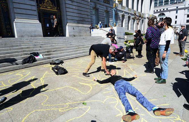Paul Aguilar, forefront, gets his body outlined as activists stage a "die-in" outside of San Francisco City Hall as part of a Back to HIV rally to highlight the continuing needs of HIV patients. Photo: Rick Gerharter