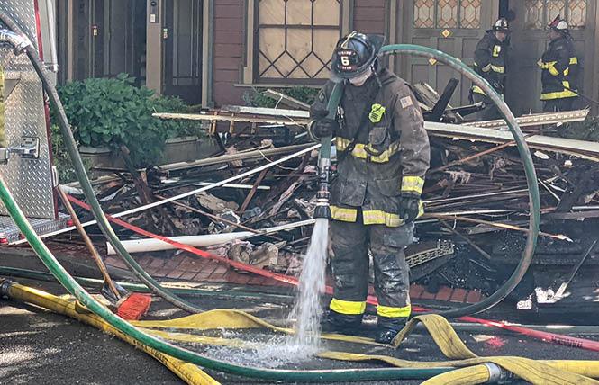 A firefighter sprays down hoses after the fire at 141 and 147 Noe Street had been extinguished Friday morning in San Francisco's Duboce Triangle neighborhood. Photo: Eric Burkett