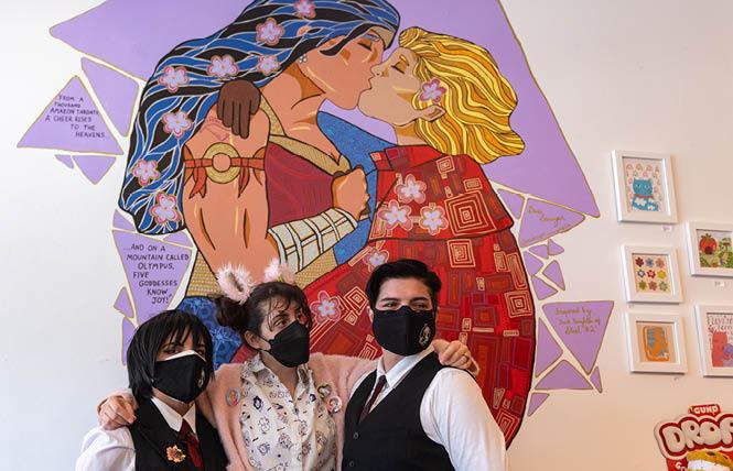 Johan Teilzeit, left, joined Sour Cherry Comics owner Leah Morrett and Michael Stevens in standing in front of artist Gus Sawyer's mural "The Kiss," showing Wonder Woman locking lips with Zala-El, Superman's sister. Photo: Jane Philomen Cleland