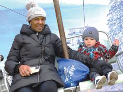 South Enders Marie Emmanuel and 22-month-old William Porter enjoy the ski lift photo booth at the February 22 Children's Winter Festival hosted by Mayor Michelle Wu and the Boston Parks and Recreation Department on Boston Common. The annual event was presented in partnership with sponsors Highland Street Foundation, L.L. Bean, Dunkin', H.P. Hood, College Hunks Hauling Junk & Moving, and media sponsor The Boston Globe. The free festival offered music, giveaways, winter activities, treats, and crafts with  attractions including inflatables such as the All-Star Challenge, Everest Climb 'N' Slide, and a Fun House Maze, train rides, slap shot hockey, snow throw, a LEGO build activity with a Master Model Builder, and more.  Photo by Jon Seamans.