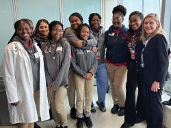 Full group shot of the 8th grade class with lecturers. From left to right: Naaysha Lerick (Dorchester), Meliah Nelson (Hyde Park), Vanessa De Los Santos (Dorchester), Faith Mogoli (Dorchester), Harmonie Johnson (Dorchester), Julyah Cene (Roslindale), Nicole Henry, MD, Nadia McBrayer (Hyde Park), Chinyere Egbuta, MD, Dr. Izabela Leahy. Photo courtesy of Elevate Communications. 